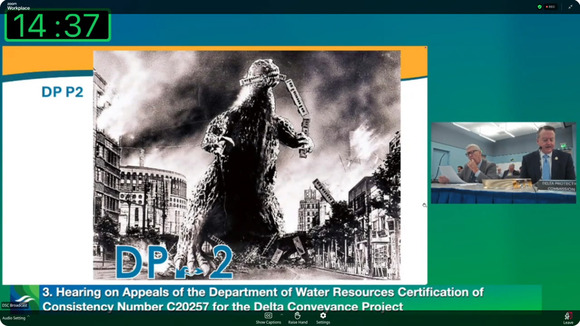 Screenshot of a hearing prominently featuring a Powerpoint slide with a large Godzilla image