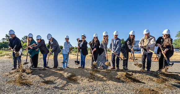 People tossing shovels of dirt at a ground-breaking