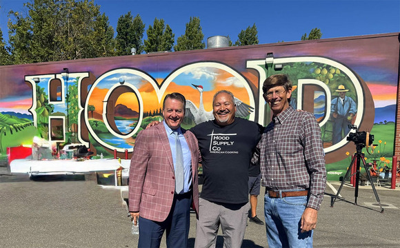 Three men posing in front of a mural