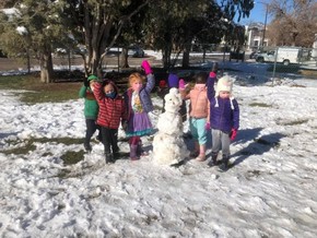 Boulder Day Nursery kids outside playing next to a snowman