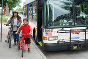 mother and son holding bikes next to city bus