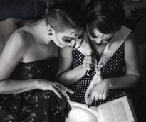 Women in costumes reading a book by flashlight