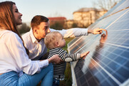 husband, wife and baby touching a solar panel