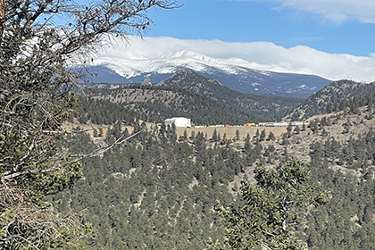 View of white construction hut on Denver Water's construction site mountains with snow in background