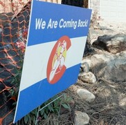 We are Coming Back sign with construction worker inside the State Flag emblem