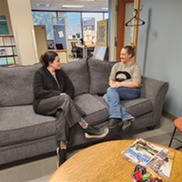 two women sitting on a couch at the recovery center talking 
