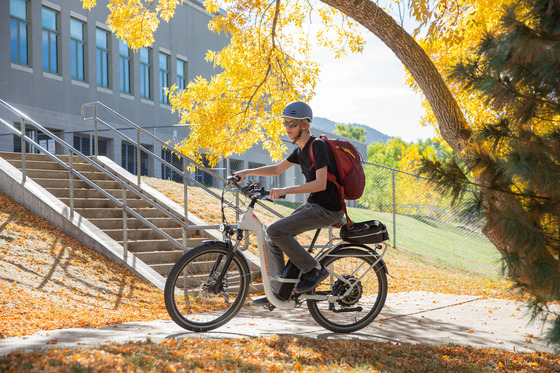 A safe youth e-bike bicycle rider wearing a helmet at a school in the fall season