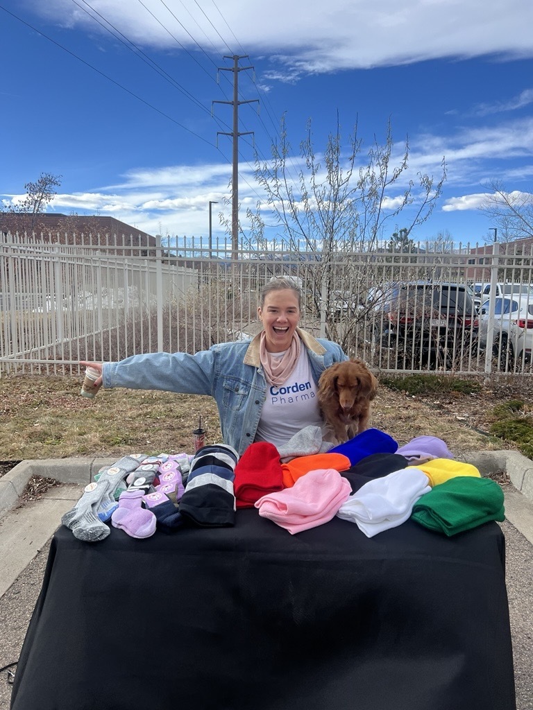 Person with puppy standing in front of a table filled with children's winter clothing