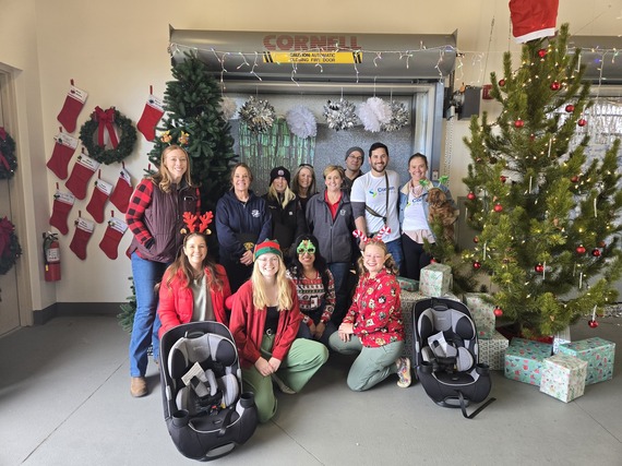 People standing and seated for a group photo amidst holiday decorations