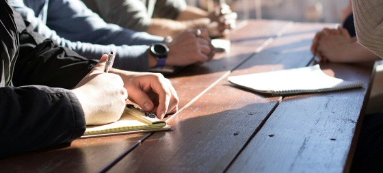 group of people taking notes in a meeting 