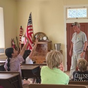 Man leads a schoolhouse activity for enthusiastic kids