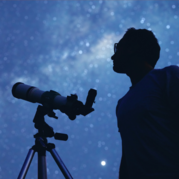 Man with a telescope looks toward the star-filled sky