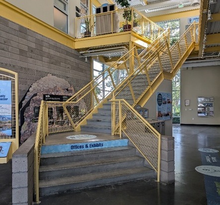 the main lobby of the recycling center with a staircase in the middle and several educational displays on the first floor