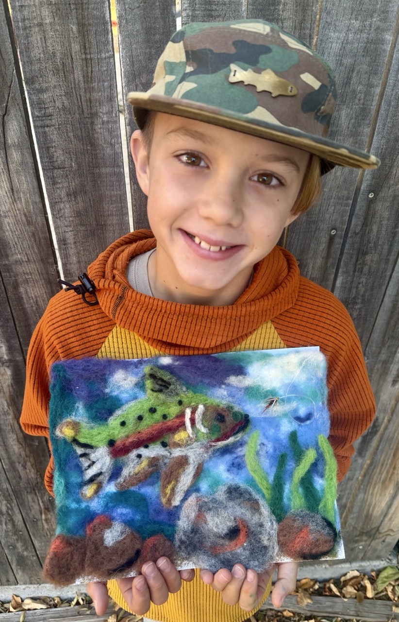 3-5 First Place Winner Wood, holding his winning art work. The art features a felted trout swimming in a river.