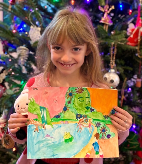 K-2 Winner Mira, holding her artwork that features a green Mother Earth overlooking a lagoon