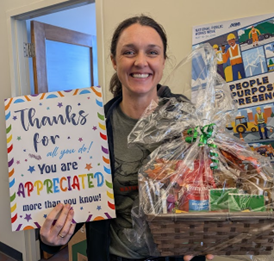 RCD staff member posing with a large thank you card and a gift basket