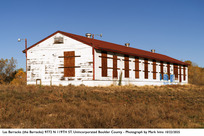 Image of Las Barracas - an old white dilapidated barrack with grass in front