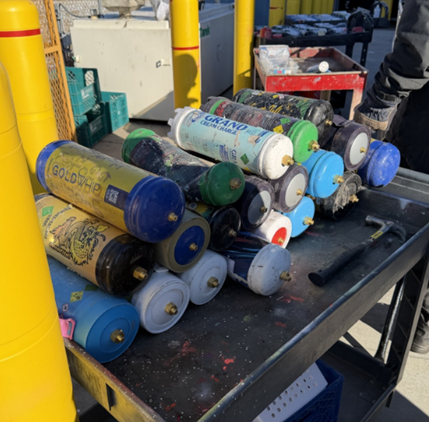 Several nitrous oxide canisters stacked on a cart waiting to be processed.