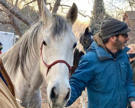 Man holding halter next to horse used in search and rescue