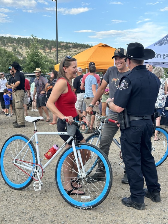 Man and woman standing with bikes talking to a police officer at National Night Out event