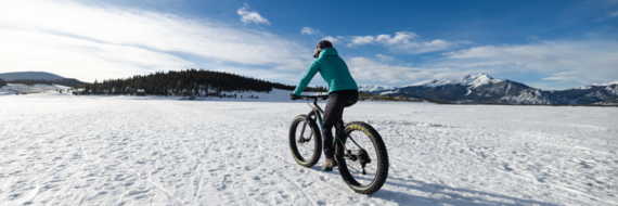  A person cycling through a snowy field, surrounded by a serene winter landscape.