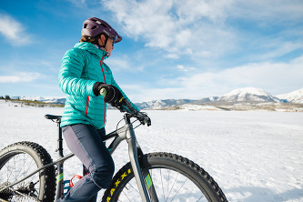  A person cycling through a snowy landscape, surrounded by white snowflakes and a wintery atmosphere