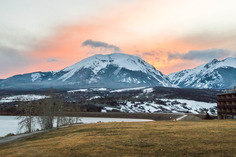 A scenic view of snow-covered mountains at sunset, with vibrant colors illuminating the sky and peaks in the background.