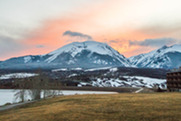A scenic view of snow-covered mountains at sunset, with vibrant colors illuminating the sky and peaks in the background.