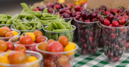 A vibrant display of fresh fruits and vegetables at a farmers market, showcasing seasonal produce in various colors.