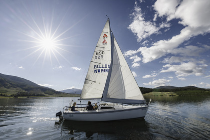 A sailboat on the water with a scenic mountain background 