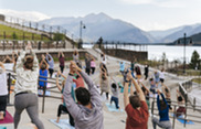 People practicing yoga on stone steps with majestic mountains rising in the background