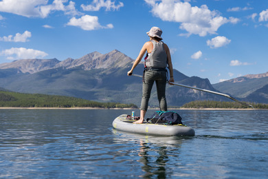 A woman paddles on a paddle board in calm water, enjoying a sunny day outdoors