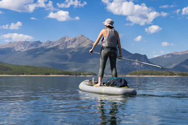 A woman paddles on a paddle board in calm water, enjoying a sunny day outdoors