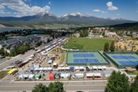 Aerial view of a tennis court surrounded by mountains, showcasing the court's vibrant colors against a natural backdrop.