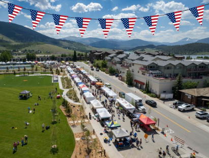 A large outdoor event featuring colorful flags and numerous tents set up for attendees.