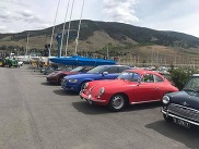 A row of classic cars parked neatly in a parking lot under clear blue skies