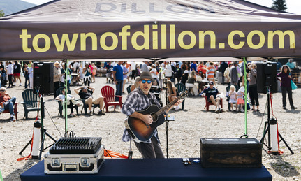 A man holds a guitar under a tent 