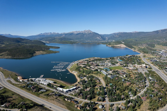 Aerial view showcasing a serene lake surrounded by majestic mountains under a clear blue sky.