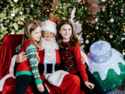 two girls smile while sitting on Santa's lap 