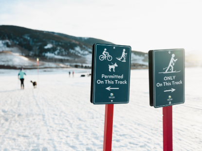 Snow-covered ground with two signs on poles, providing information in a cold, wintry setting