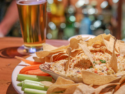 A plate of nachos and a beer are represented 