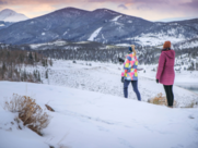 Two hikers walk on a snowy trail 