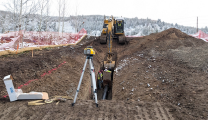 A back plow is digging a dirt hole on a hillside 
