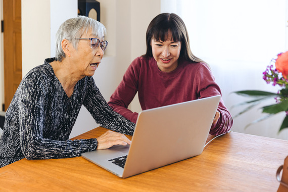 Older adult receiving help using a laptop from a younger woman