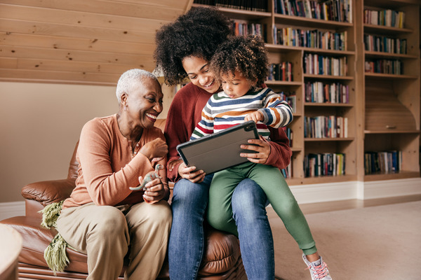 Grandmother, mother, and daughter sitting together using a tablet.