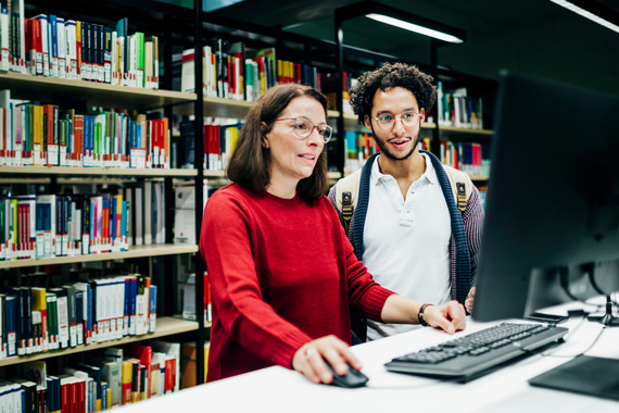 Woman in library on a laptop next to a man