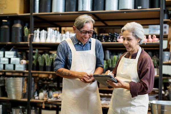 Two adults in aprons looking at tablets