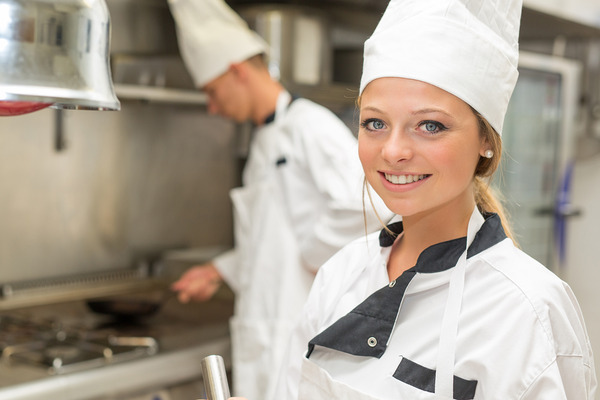 Female culinary apprentice in an apron and chefs hat