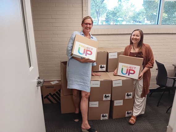 Two women holding carboard boxes and smiling