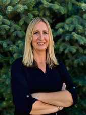 Image of blond woman with arms crossed and smiling at camera